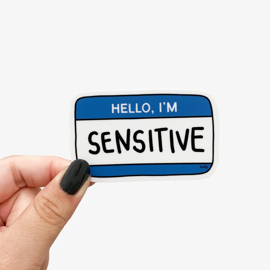 A funny sticker featuring a blue name tag and text that reads, Hello, I’m Sensitive.
